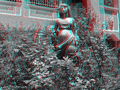 Statue of a pretty woman in a rose garden.