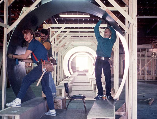 Men constructing tubes out of sheet metal for a movie set